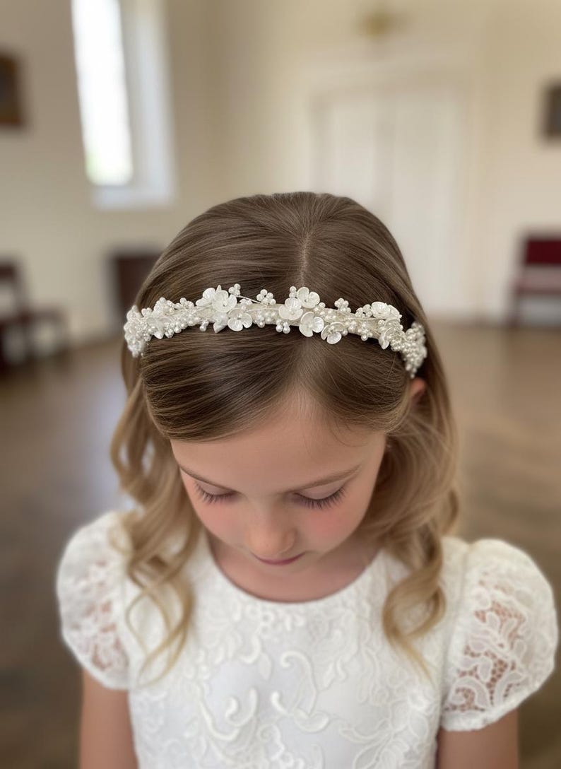 May include: A white floral headband with pearl accents. The headband features small, delicate white flowers and pearls, creating a refined and elegant look. This accessory is suitable for special occasions and celebrations.