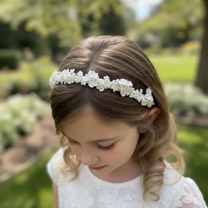 May include: A white floral headband with pearl accents. The headband features small, delicate flowers and pearls, creating a refined and elegant look. Perfect for special occasions, this accessory adds a touch of sophistication. The headband is designed to be worn on the head.