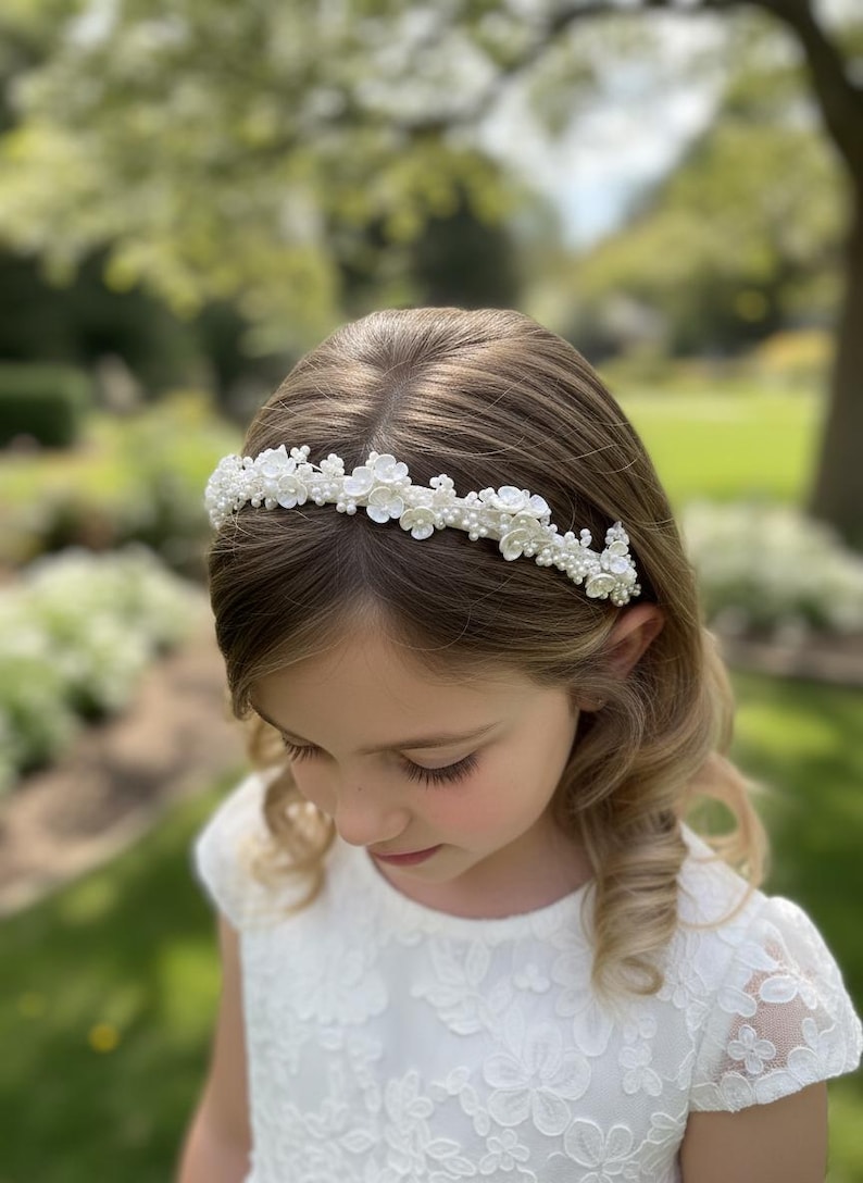 May include: A white floral headband with pearl accents. The headband features small, delicate flowers and pearls, creating a refined and elegant look. Perfect for special occasions, this accessory adds a touch of sophistication. The headband is designed to be worn on the head.