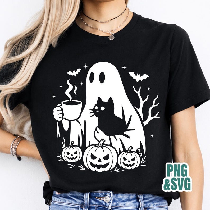 Pode incluir: Uma t-shirt preta com um gr&aacute;fico branco de um fantasma segurando uma caneca fumegante e um gato preto, rodeado por tr&ecirc;s ab&oacute;boras, morcegos e ramos de &aacute;rvore nus. O texto PNG & SVG est&aacute; impresso no canto inferior direito da imagem.