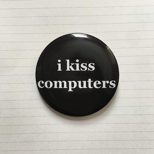 May include: A black button with white text that reads "i kiss computers".