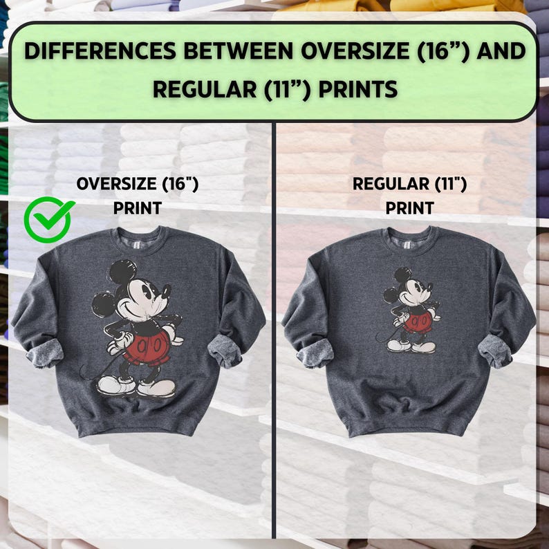 Puede incluir: Dos sudaderas grises oscuras con dise&ntilde;os de Mickey Mouse. La sudadera izquierda tiene una impresi&oacute;n m&aacute;s grande de 40 cm, mientras que la derecha tiene una impresi&oacute;n regular de 28 cm. El texto en la parte superior dice "DIFFERENCES BETWEEN OVERSIZE (16") AND REGULAR (11") PRINTS."