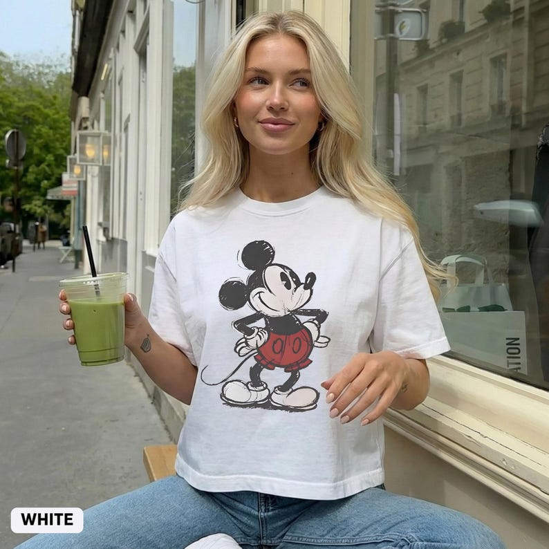 Puede incluir: Camiseta blanca con un gr&aacute;fico desgastado de Mickey Mouse en negro, rojo y blanco. La camiseta tiene mangas cortas y cuello redondo. La palabra "WHITE" est&aacute; impresa en la parte inferior de la imagen.