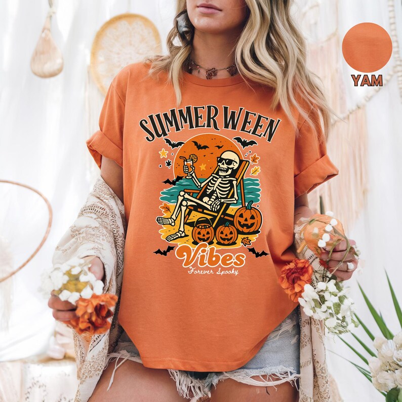May include: Orange t-shirt with the text "Summerween Vibes Forever Spooky". The graphic features a skeleton relaxing on a beach chair with pumpkins and bats. The shirt is a yam color.
