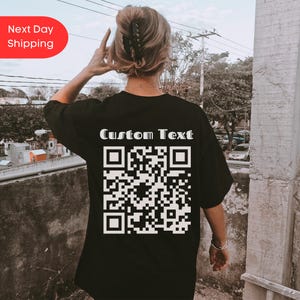 May include: Black t-shirt with a white QR code and the text "Custom Text" printed on the back.