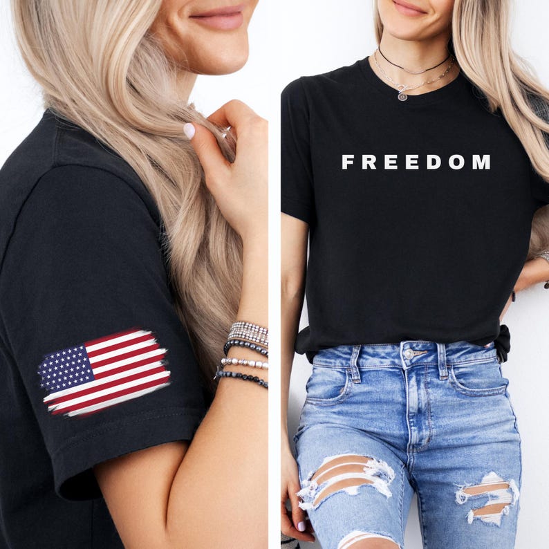 K&ouml;nnte beinhalten: Zwei schwarze T-Shirts. Eines hat das Wort "FREEDOM" in wei&szlig;en Blockbuchstaben. Das andere hat ein abgenutztes amerikanisches Flaggen-Design auf dem &Auml;rmel. Beide werden mit blauen Jeans getragen.