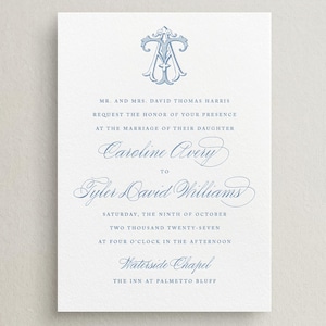May include: A formal wedding invitation on textured white paper. The text is in a delicate blue script, with the names "Caroline Avery" and "Tyler David Williams" prominently displayed. The invitation includes the date, time, and location.