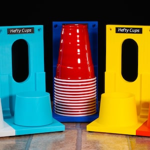 May include: Four colorful cup holders in white, blue, yellow, and red. Each holder has a rectangular back with an oval opening and a base to hold a cup. The text "Hefty Cups" is printed on each holder.