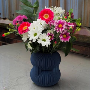 Peut inclure: Un bouquet de fleurs roses, blanches et rouges dans un vase bleu texturé. Le vase a un design arrondi à double couche.