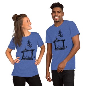 May include: Blue short-sleeved t-shirts with a black graphic design. The design shows a stylized illustration of a creature jumping out of a square frame. The shirts are worn by a woman and a man.