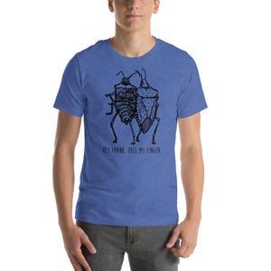 Könnte beinhalten: Ein blaues T-Shirt mit einer schwarz-weißen Illustration von zwei Insekten. Der Text "Hey Frank, pull my finger" ist unter der Illustration aufgedruckt.