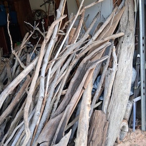 Puede incluir: Una colección de piezas de madera flotante desgastada de varias formas y tamaños. La madera varía en color desde gris claro hasta marrón oscuro, con texturas y nudos visibles. Algunas piezas son largas y delgadas, otras gruesas y nudosas, aptas para manualidades o decoración.