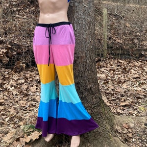 May include: Rainbow bell bottom pants with a black waistband and a drawstring. The pants are made of a soft, stretchy fabric and have a comfortable fit.