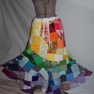 May include: A colorful patchwork skirt with a rainbow of colors and patterns. The skirt is made of many different fabrics, including floral prints, geometric patterns, and solid colors. The skirt is gathered at the waist and has a flowing, A-line silhouette.