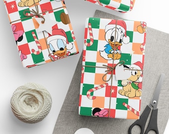 Puede incluir: Papel de regalo con un patrón repetitivo de personajes de Disney, incluidos Pluto y Donald Duck con gorros de Papá Noel, intercalados con bastones de caramelo y estrellas sobre un fondo a cuadros rojo, verde, naranja y blanco con cordel.