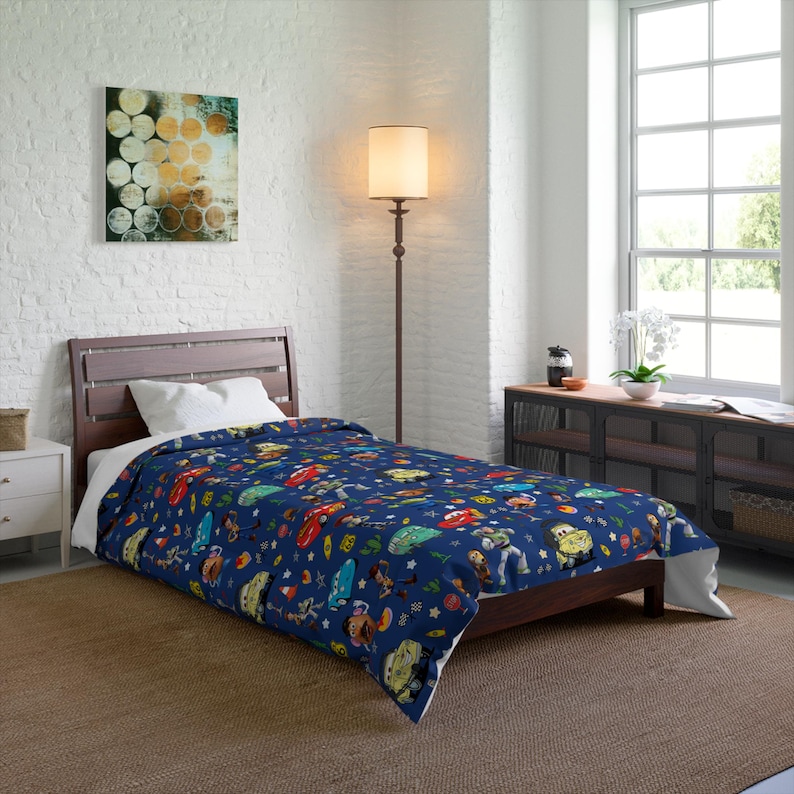 May include: A dark blue single duvet cover featuring a repeating pattern of various animated characters from the Toy Story and Cars film franchises, including Lightning McQueen, Buzz Lightyear, and Woody, scattered across the fabric surface.