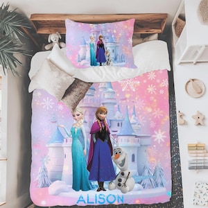 Könnte beinhalten: Ein rosa-lila Bettwäsche-Set mit Figuren aus dem Film Frozen. Das Set enthält einen Bettbezug und einen Kissenbezug mit Bildern von Elsa, Anna, Olaf und einem Schloss. Der Name "ALISON" ist auf dem Bettbezug aufgedruckt.
