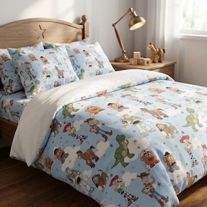 Puede incluir: Un juego de cama azul claro con un patr&oacute;n repetitivo de varios personajes de dibujos animados, incluyendo un vaquero, un guardi&aacute;n espacial, un dinosaurio verde, una figura con forma de patata y un caballo marr&oacute;n, entre nubes y estrellas.