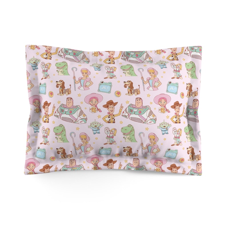 May include: A rectangular pillowcase featuring a repeating pattern of Toy Story characters including Woody, Buzz Lightyear, Bo Peep, Rex, Slinky Dog, and Forky on a light pink background with small yellow stars and light blue rectangular speech bubbles.