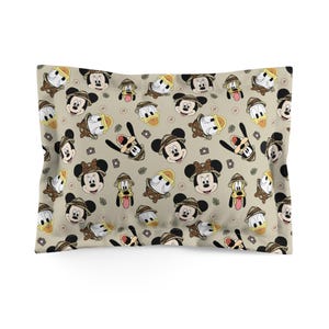 Pu&ograve; includere: Federa beige con un motivo ripetuto di Topolino, Paperino e Pippo in tenuta da safari. Il design include fotocamere e cappelli da safari, creando un tema giocoso e avventuroso.