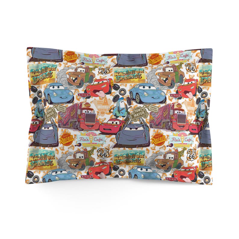 Pode incluir: Uma fronha com um padr&atilde;o repetido de carros e caminh&otilde;es de desenho animado. O design inclui personagens do filme Carros, com os logotipos da Rota 66 e Rusteze. A paleta de cores inclui vermelho, azul, marrom e cinza.