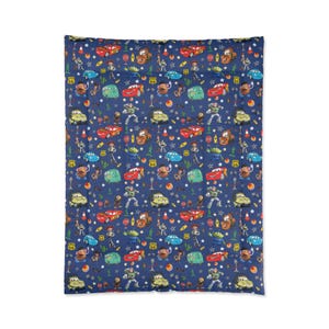 May include: A rectangular blanket featuring a dark blue background with a repeating pattern of characters from the Cars and Toy Story movies, including red race cars, green aliens, cowboys, and potato figures, interspersed with stars and road signs.