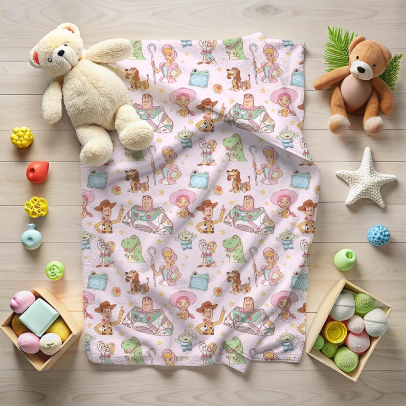May include: A light pink baby blanket with a repeating pattern of cartoon characters. The blanket features a cowboy, a space ranger, a sheep herder, a green dinosaur, and other characters. Toys surround the blanket.