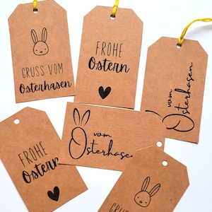 Può includere: Sei etichette regalo in carta marrone con inchiostro nero. Le etichette presentano illustrazioni di conigli e il testo "Frohe Ostern" (Buona Pasqua) e "Gruss vom Osterhasen" (Saluti dal coniglio pasquale).