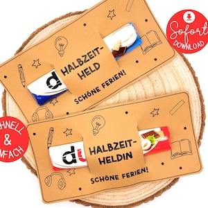 Könnte beinhalten: Zwei braune Geschenkkarten mit dem Text "HALBZEIT-HELD" und "SCHÖNE FERIEN!". Jede Karte hat einen Schokoriegel, der aus einem Schlitz herausschaut. Die Karten sind mit Illustrationen einer Glühbirne, eines Bleistifts, Kopfhörern, Sternen und einem Buch verziert.