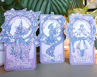 May include: Three illustrated tarot cards with a pink background and blue outlines. The cards depict a wizard, a knight on a dragon, and a person holding a staff. The cards are titled "The Arcane", "The Lance", and "Illumina".