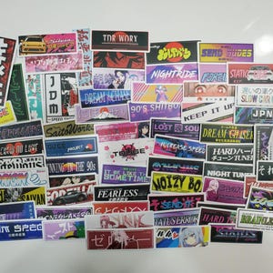 Może przedstawiać: Zbiór kolorowych naklejek z japońskim tekstem i grafiką. Naklejki przedstawiają różne wzory, w tym samochody, postacie z anime i wzory geometryczne. Naklejki idealnie nadają się do dekorowania laptopów, butelek z wodą i innych przedmiotów osobistych.