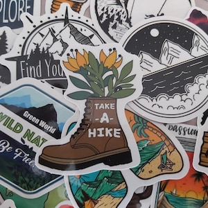 May include: A collection of colourful stickers with nature and travel themes. The stickers feature images of mountains, trees, a boot with the text "Take a Hike", a beach scene, and a green sticker with the text "Wild Nature, Green World, Be Free".