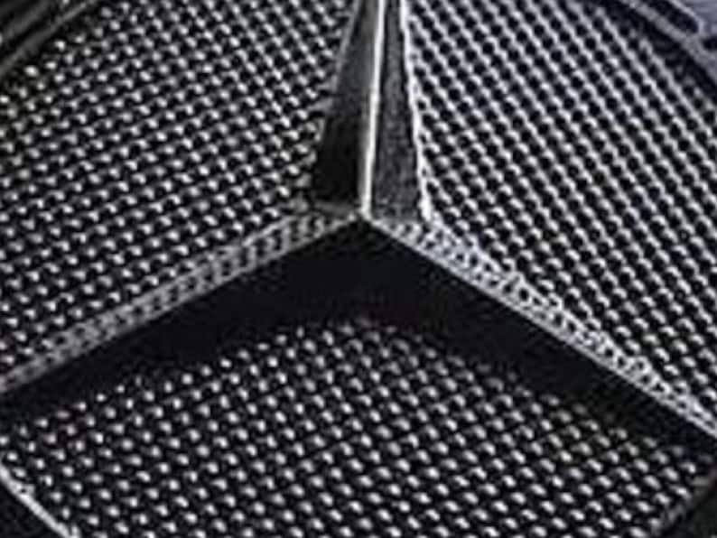 May include: A close-up of a black, three-pointed star logo with a textured surface.