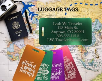 Op de afbeelding: Vier kleurrijke bagagelabeltjes met verschillende reisgerelateerde spreuken. De labeltjes zijn van metaal en hebben een gat voor een touwtje. De spreuken op de labeltjes zijn "Travel is my Therapy", "Went Everywhere But it's on my list", "Save Travel, Repeat", en "Take the Road".