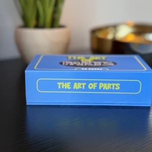 May include: Blue box with the text "The Art of Parts" on the front. The box is for a game called "The Art of Parts" and has a yellow and black design.