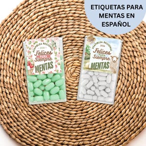 May include: Two clear plastic boxes filled with mints, one green and one white, sit on a woven mat. Each box has a label with the text "ASAMBLEA REGIONAL 2026 Felices PARA Siempre MENTAS". The text "ETIQUETAS PARA MENTAS EN ESPAÑOL" is also visible.