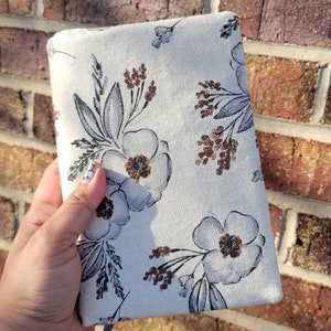 May include: A white fabric journal cover with a floral pattern in shades of blue, brown, and gray. The cover has a gray ribbon bookmark.
