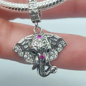 Puede incluir: Un charm de plata en forma de elefante con cristales rosas y blancos. El elefante tiene detalles intrincados y un diseño delicado.