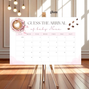 Pode incluir: Um calendário branco em cavalete de madeira com o texto "GUESS THE ARRIVAL of baby Nova". Apresenta uma chávena de café rosa e um laço. O calendário é para abril, com datas de 1 a 31.