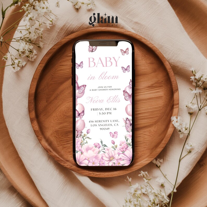 May include: A pink and white baby shower invitation with butterflies and flowers. The text reads "Baby in Bloom" and includes the name "Nova Ellis", the date "Friday, Dec 16", the time "5:30 PM", the address "456 Serenity Lane, Los Angeles, CA 90049".