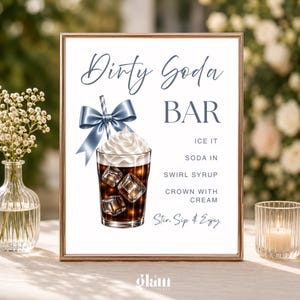 May include: A rectangular sign in a rose gold frame featuring the text Dirty Soda BAR, ICE IT, SODA IN, SWIRL SYRUP, CROWN WITH CREAM, and Stir, Sip & Enjoy. An illustration shows a glass of dark soda with ice, whipped cream, and a blue bow.