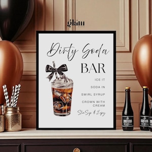May include: A black framed sign with the words "Dirty Soda Bar" in elegant script. The sign includes a graphic of a soda drink with ice cubes, a bow, and a list of ingredients. The sign is on a white surface.