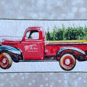 May include: A red vintage pickup truck with a green Christmas tree in the bed. The truck has a sign that says "Merryville Tree Farm" and "Cut Your Own - Pre-Cut".