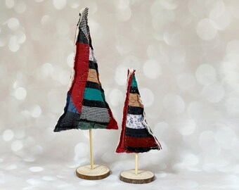May include: Two patchwork fabric Christmas trees on wooden bases. The larger tree is red, black, white, and green. The smaller tree is red, black, white, and brown.