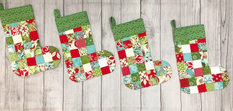 May include: Four patchwork Christmas stockings in red, green, white, and blue with a green and white checkered cuff.