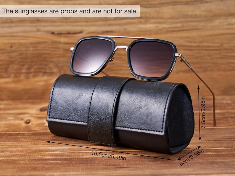 May include: Black leather sunglasses case with a strap closure. The case is 6.49 inches long, 2.36 inches wide, and 2.95 inches high. Sunglasses are not for sale.