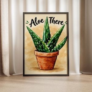 May include: A framed wall art print featuring a watercolor illustration of a green aloe vera plant in a terracotta pot against a tan background. The text "Aloe There" is written in black script above the plant, with small green leaf accents.