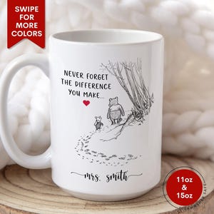May include: White ceramic mug featuring a black and white illustration of Winnie the Pooh and Piglet walking. The mug has the text "Never forget the difference you make..." and "mrs. smith". Available in 11oz and 15oz sizes.