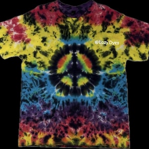 Op de afbeelding: Een tie-dye t-shirt met een vredesteken ontwerp. De shirt heeft een levendige mix van kleuren, waaronder geel, rood, blauw en paars. De tekst "@Lazy.Dyes" is zichtbaar op de shirt. De shirt heeft korte mouwen en een ronde hals.