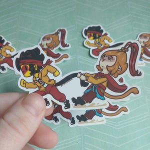 May include: A collection of cartoon stickers featuring characters in action poses. The characters are dressed in red and yellow outfits with black accents. One character is pulling a black rope, while others are running.